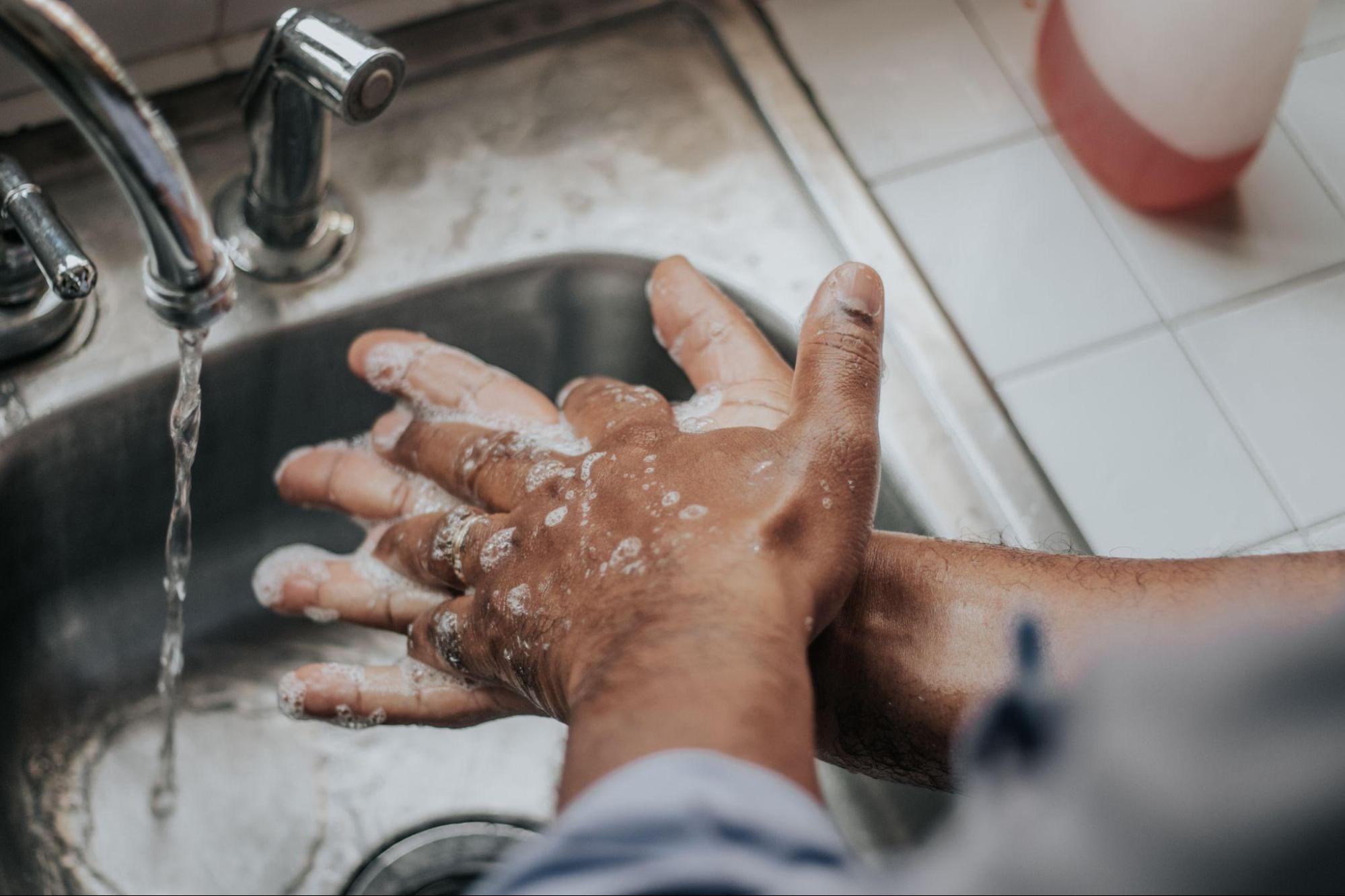  A person washing their hands at the kitchen sink.